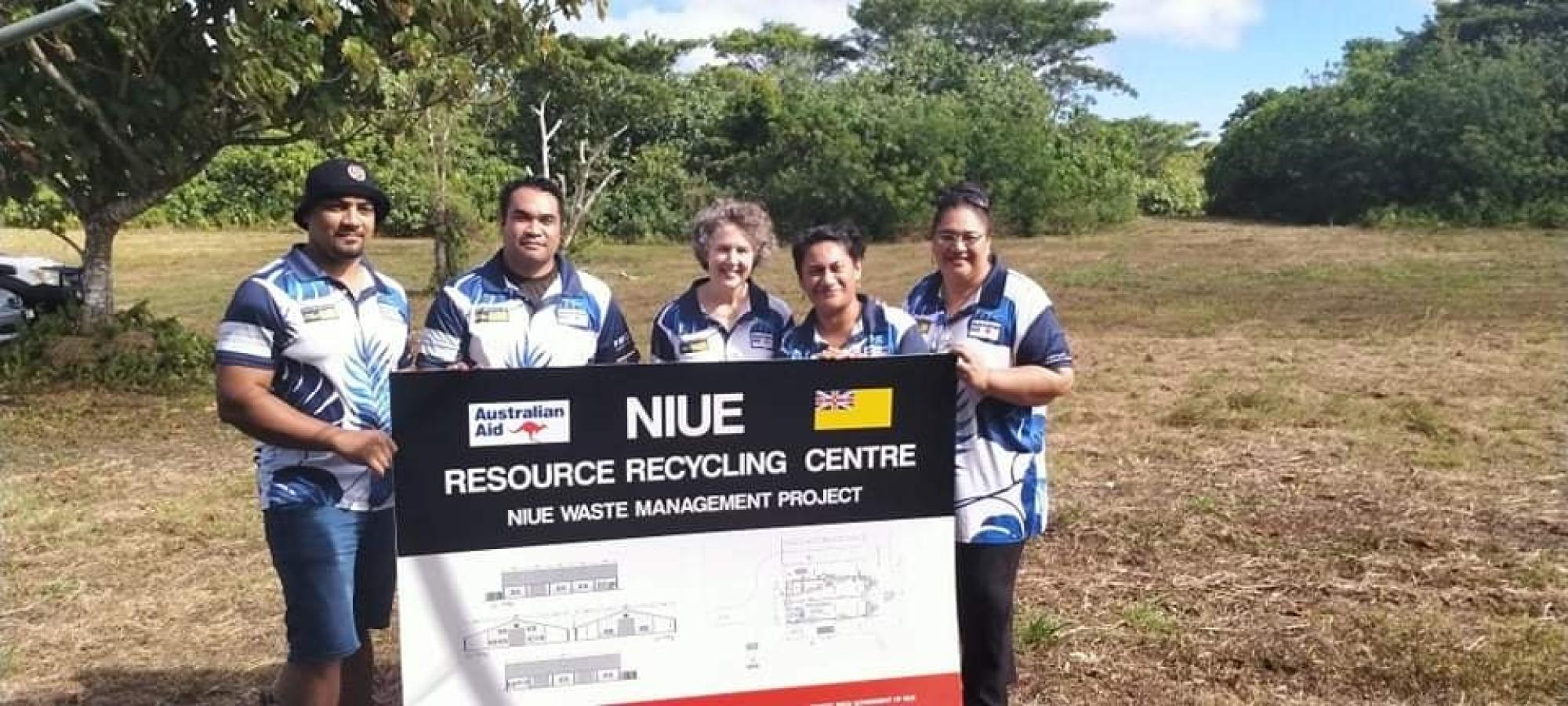 Project representatives holding the Niue Resource Recycling Centre site plan at Hikufenoga